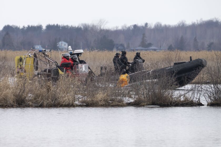 Searchers look for victims in Akwesasne, Quebec, Friday, March 31, 2023. Authorities in the Mohawk Territory of Akwesasne said Friday one child is missing after the bodies of six migrants of Indian and Romanian descent were pulled from a river that straddles the Canada-U.S. border. (Ryan Remiorz/The Canadian Press via AP)