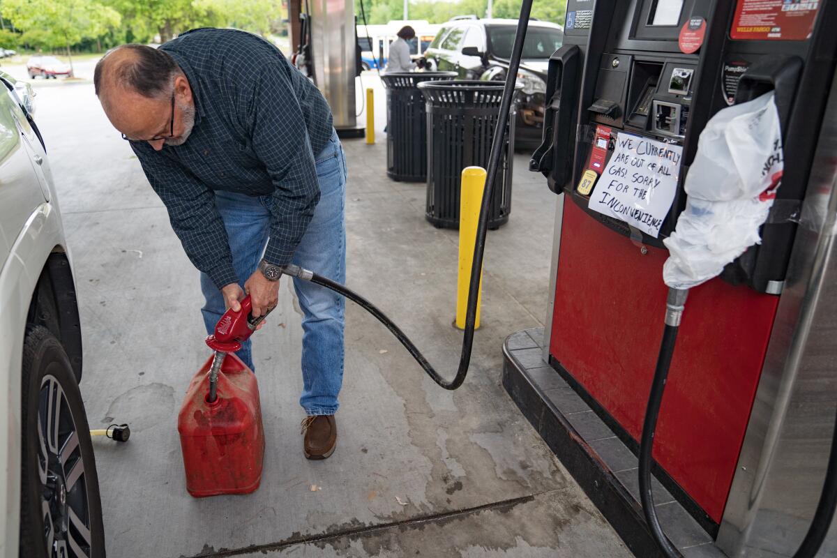 A man fills up a plastic container at a gas station 