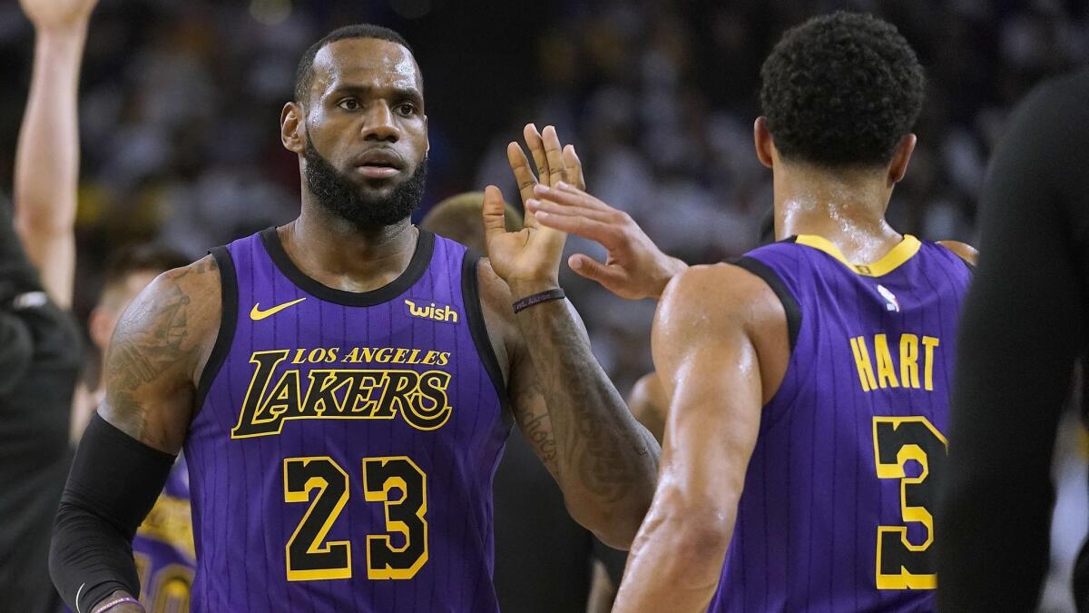 Lakers star LeBron James, left, high-fives teammate Josh Hart during a game against the Golden State Warriors on Christmas Day.