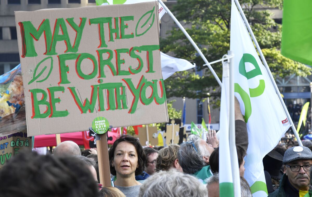A protestor holds up a sign during a climate march in Brussels, Sunday, Oct. 10, 2021. Some 80 organizations are joining in a climate march through Brussels to demand change and push politicians to effective action in Glasgow later this month.(AP Photo/Geert Vanden Wijngaert)