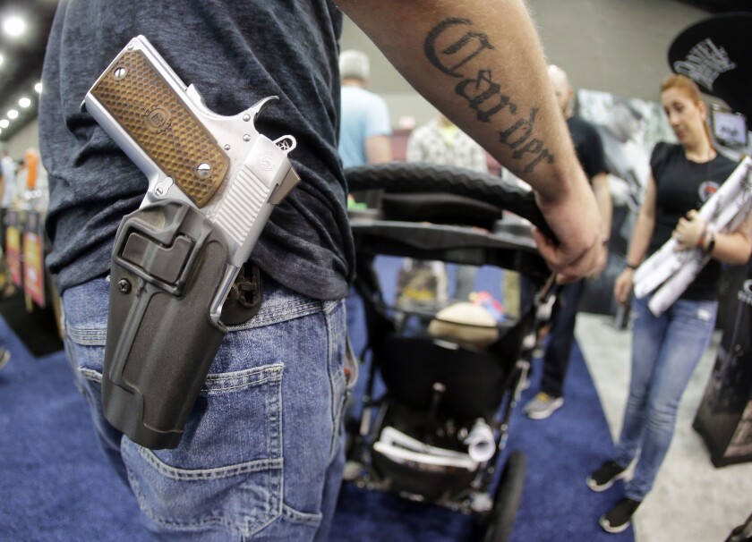 A man with a handgun in a holster pushing a baby stroller