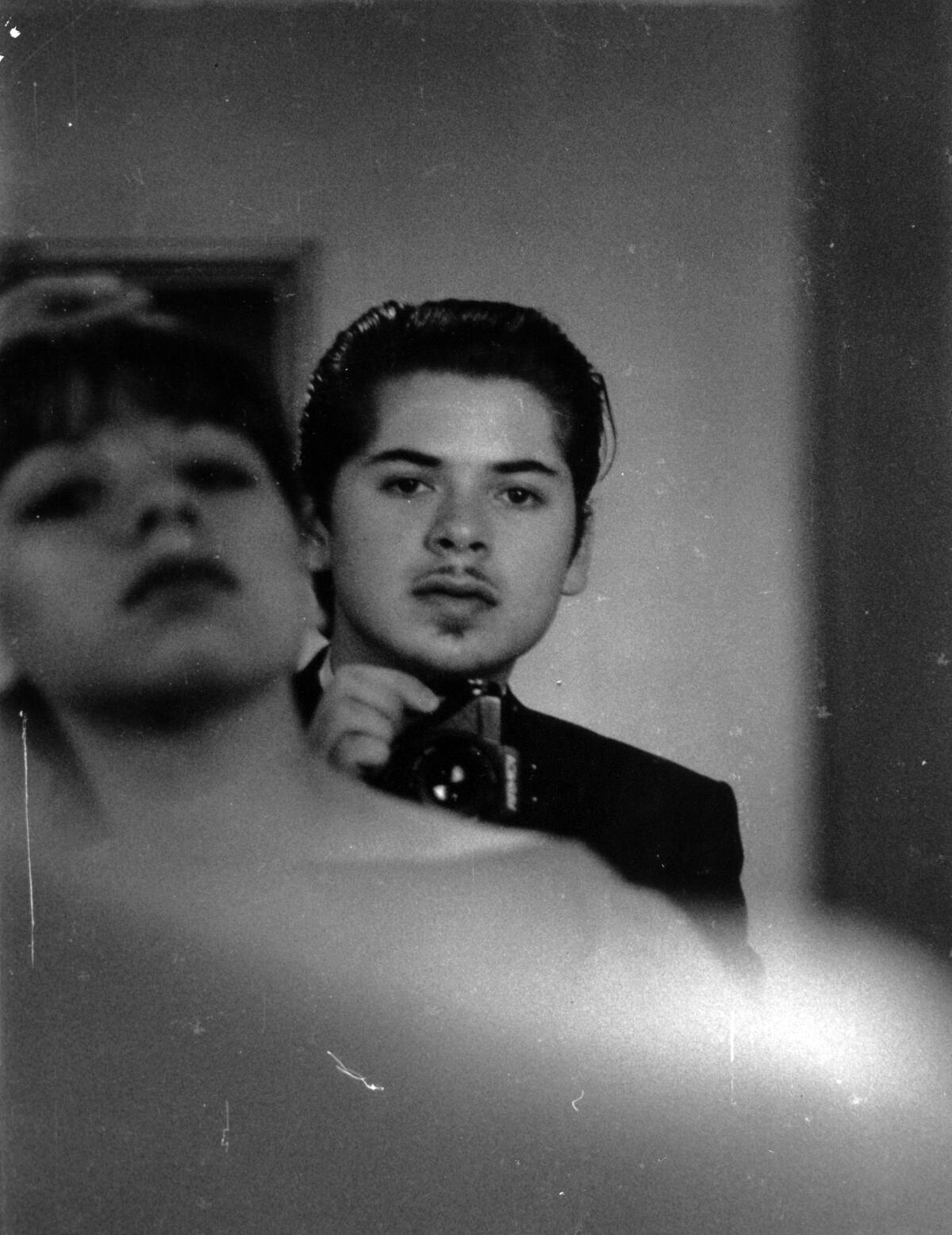Photographer Reynaldo Rivera is seen in a mirror's reflection, photographing over his sister's shoulder