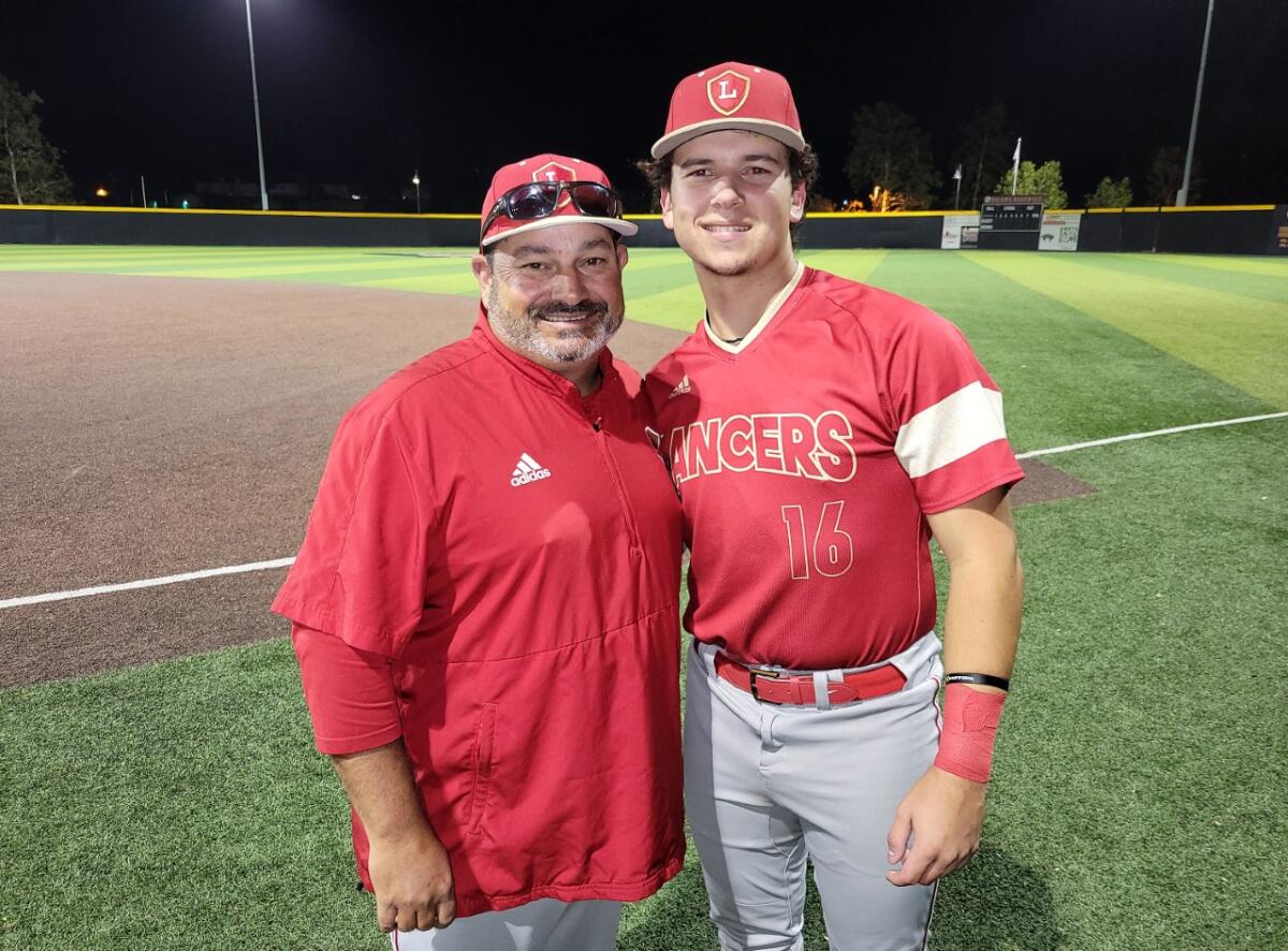 Orange Lutheran coach Eric Borba stands with son Casey Borba with a baseball field behind them.
