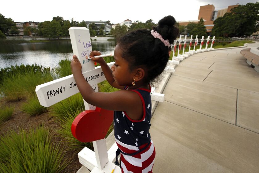 Inaya Bava, 5, on June 16, 2016, draws on crosses set up to remember the victims of the Pulse nightclub shooting at the Orlando Regional Medical Center.