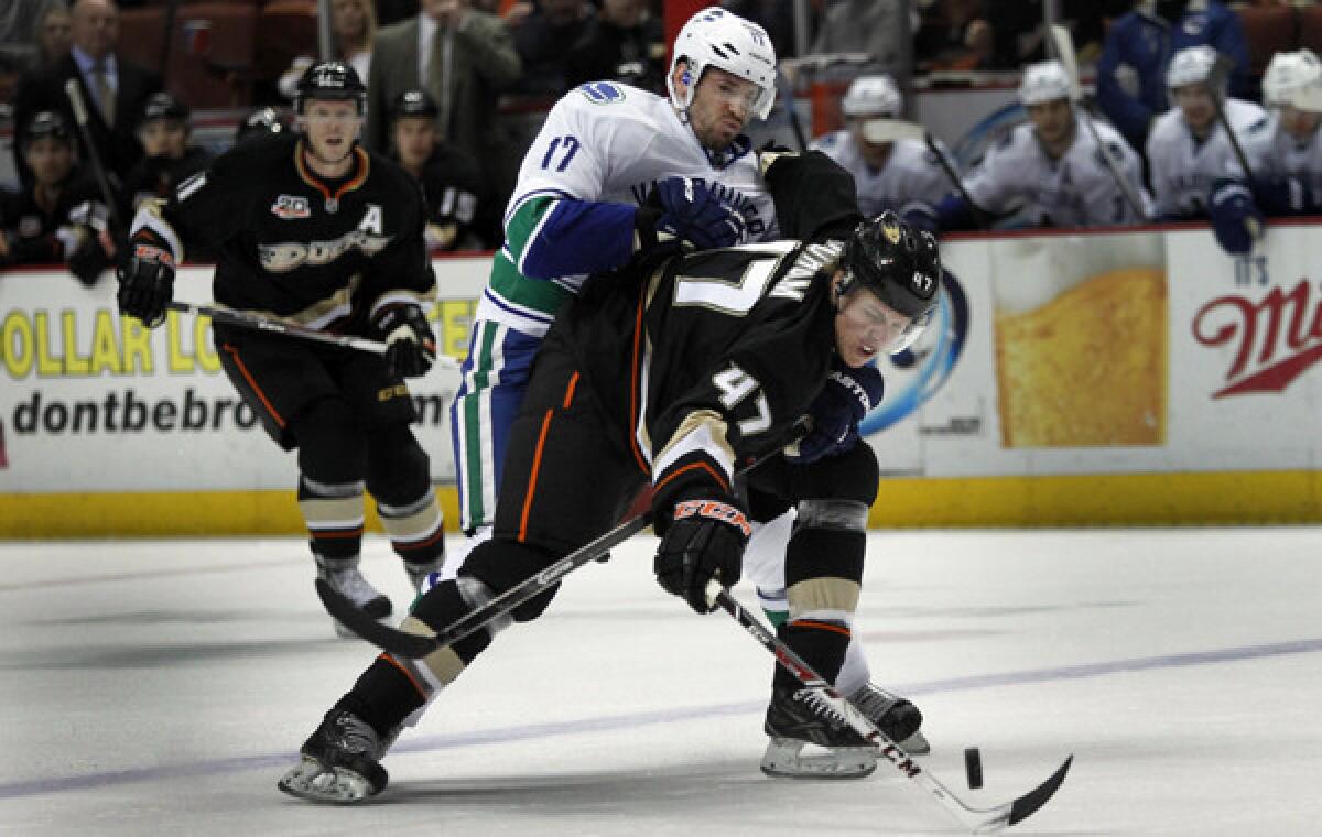 Ducks defenseman Hampus Lindholm, right, fends off Vancouver Canucks center Ryan Kessler while chasing down a loose puck during a game in January. Lindholm, a rookie who was the Ducks' top draft pick in 2012, has responded well to the workload the Ducks have given him on and off the ice.