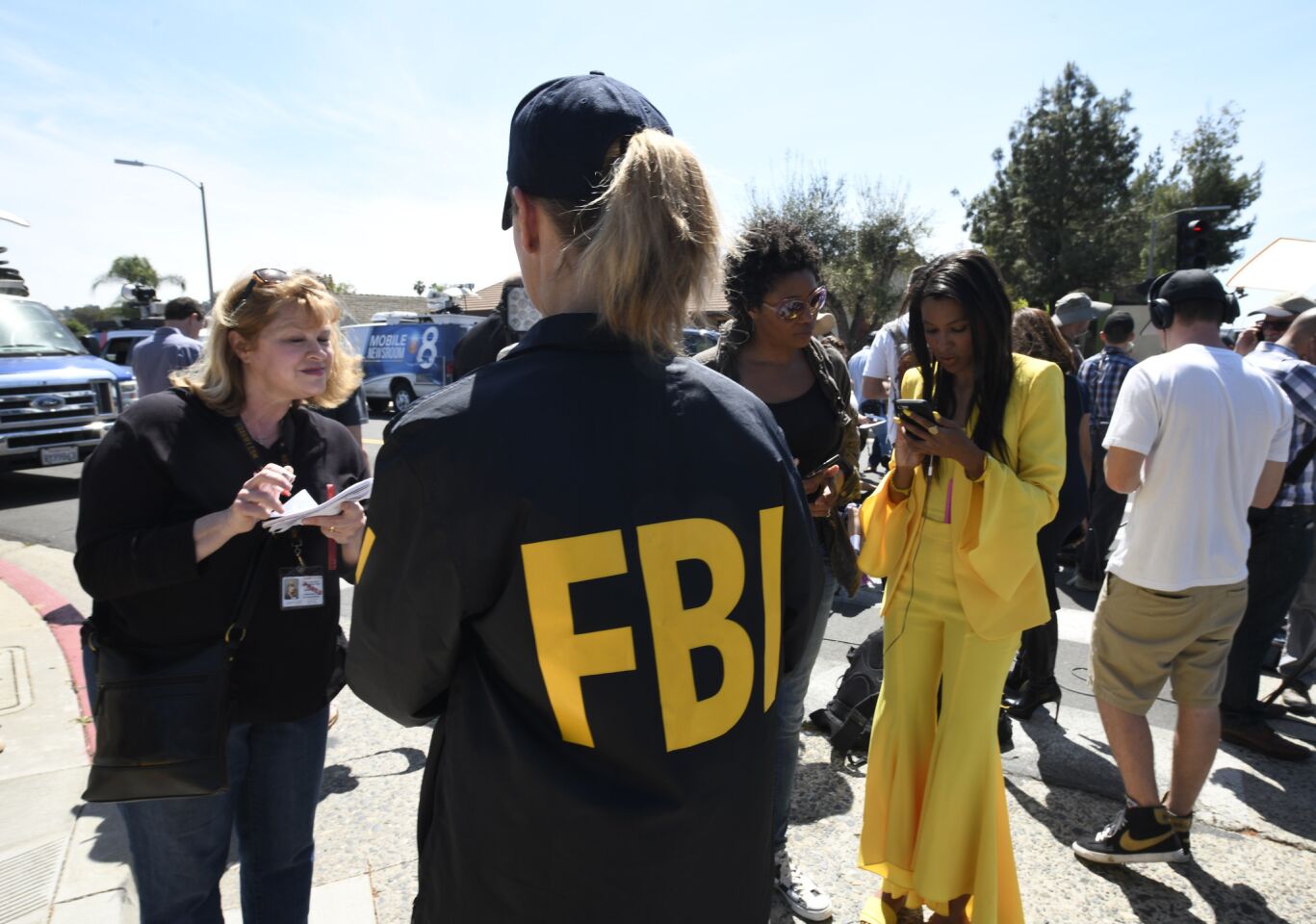 An FBI agent gives information to the media outside Chabad of Poway on Saturday.