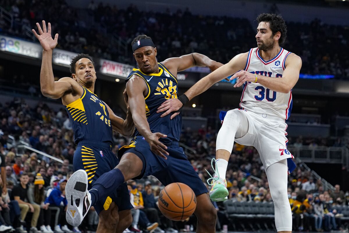 Indiana Pacers center Myles Turner (33) kicks away the pass from Philadelphia 76ers guard Furkan Korkmaz (30) during the first half of an NBA basketball game in Indianapolis, Saturday, Nov. 13, 2021. (AP Photo/Michael Conroy)