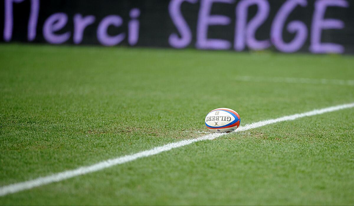 A rugby ball lies on the pitch at the Stade des Alpes stadium in France.