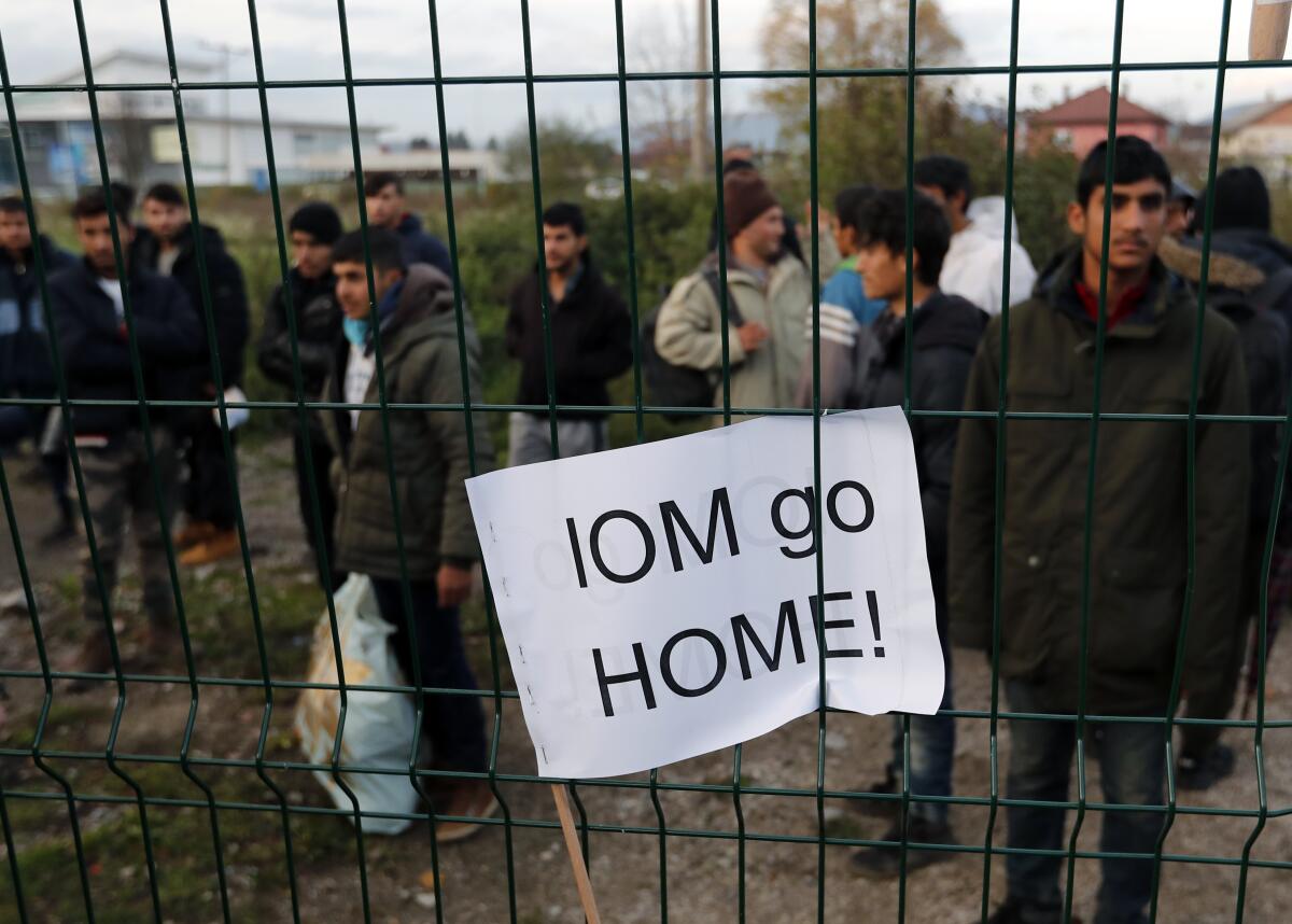 Migrants at the Bira refugee camp in Bihac, northwest Bosnia, watch protesters demanding their relocation and the closure of overcrowded camps. A banner stuck in the fence reads "IOM go home!" referring to the International Organization for Migration.