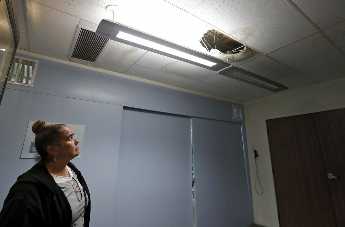 Operations Manager Debbie Wayns looks up at a hole in the ceiling.