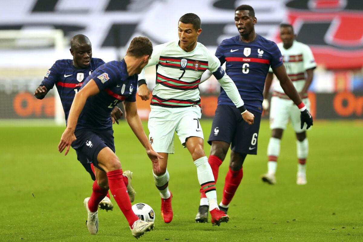 FILE - In this Sunday, Oct. 11, 2020 file photo Portugal's Cristiano Ronaldo, center, runs with the ball at France's Benjamin Pavard, foreground, between Ngolo Kante and Paul Pogba, right, during the UEFA Nations League soccer match between France and Portugal at the Stade de France in Saint-Denis, north of Paris, France. The Portuguese soccer federation says Cristiano Ronaldo has tested positive for the coronavirus. The federation says Ronaldo is doing well and has no symptoms. He has been dropped from the country's Nations League match against Sweden on Wednesday, Oct. 14. (AP Photo/Thibault Camus, File)
