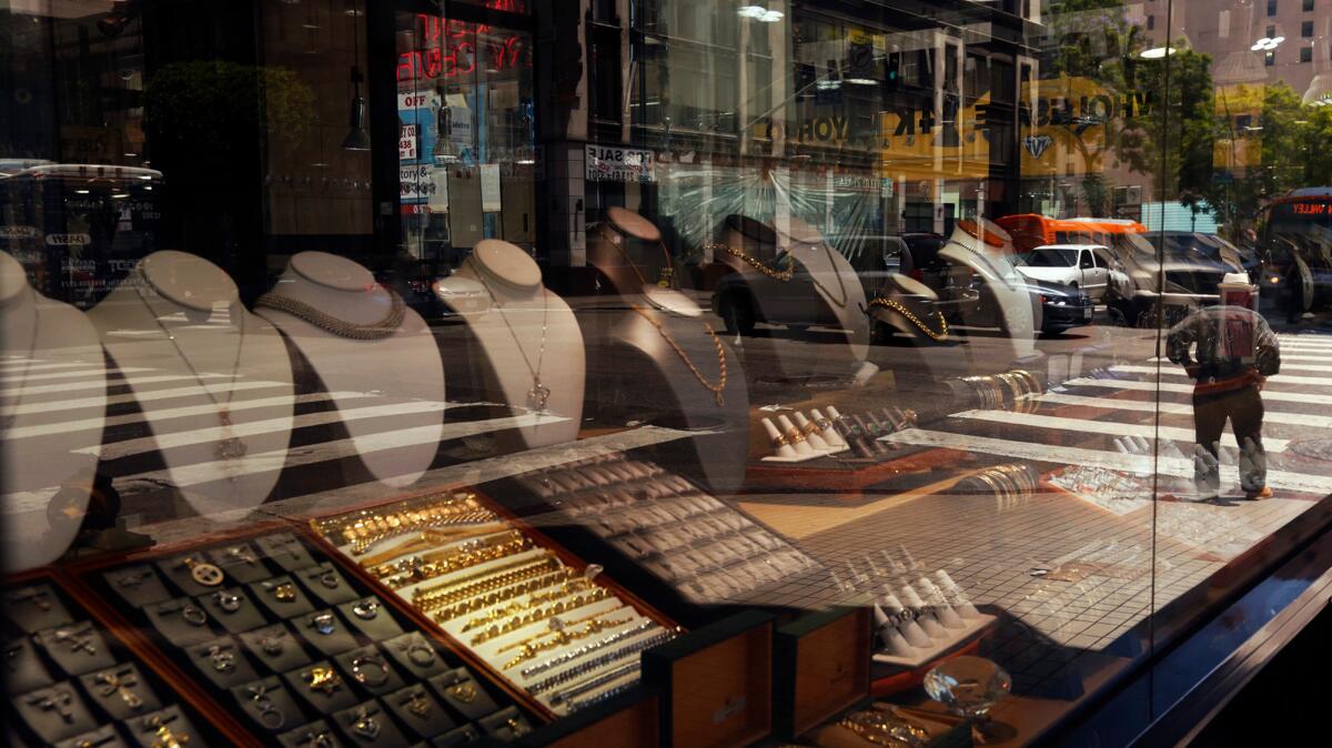 A pedestrian is reflected in a storefront window of the Albert Jewelry shop at the St. Vincent Jewelry Plaza at Hill and 7th streets in downtown Los Angeles.