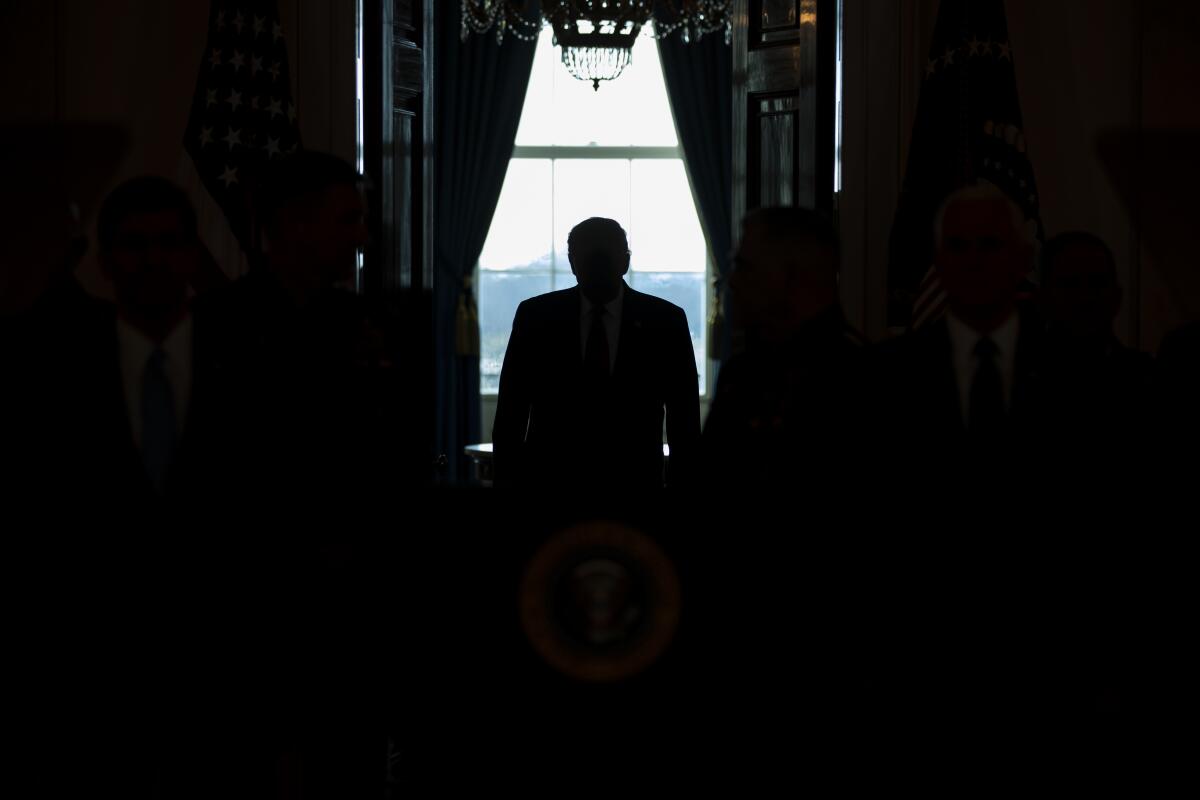 President Trump shown in the dark in front of a window.