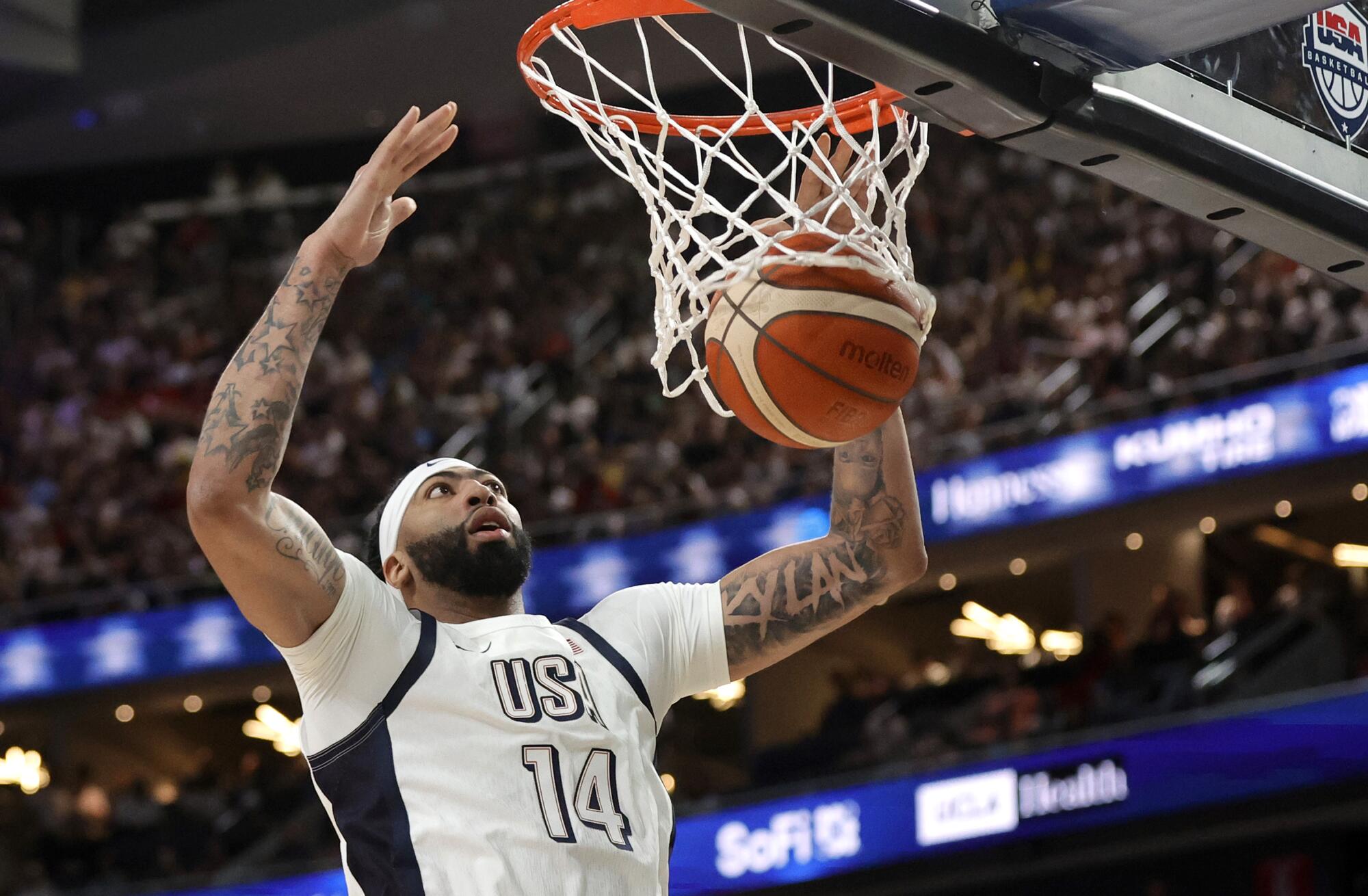 Lakers forward Anthony Davis hangs at the rim after dunking against Canada in an exhibition game Wednesday in Las Vegas.