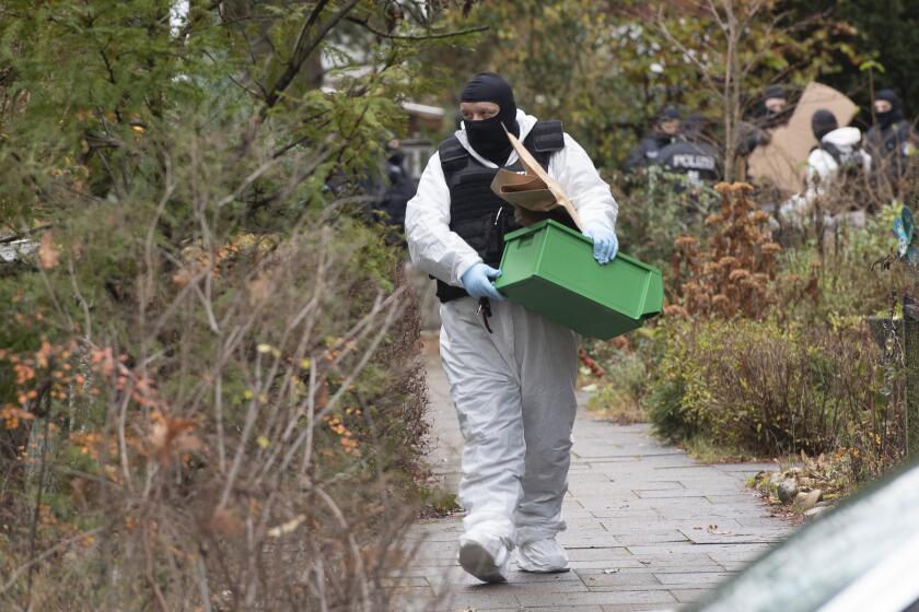 FILE - A police officer carries a plastic box during a raid against so-called 'Reich citizens' in Berlin, Germany, Wednesday, Dec. 7, 2022. Nine people charged in connection with an alleged far-right plot to topple the German government are going on trial in one of three cases linked to the plot that came to light in late 2022. The trial that opens Monday in Stuttgart is the first one and focused on those defendants of the so-called Reich Citizens group who allegedly were part of the so-called military arm. (Paul Zinken/dpa via AP, File)