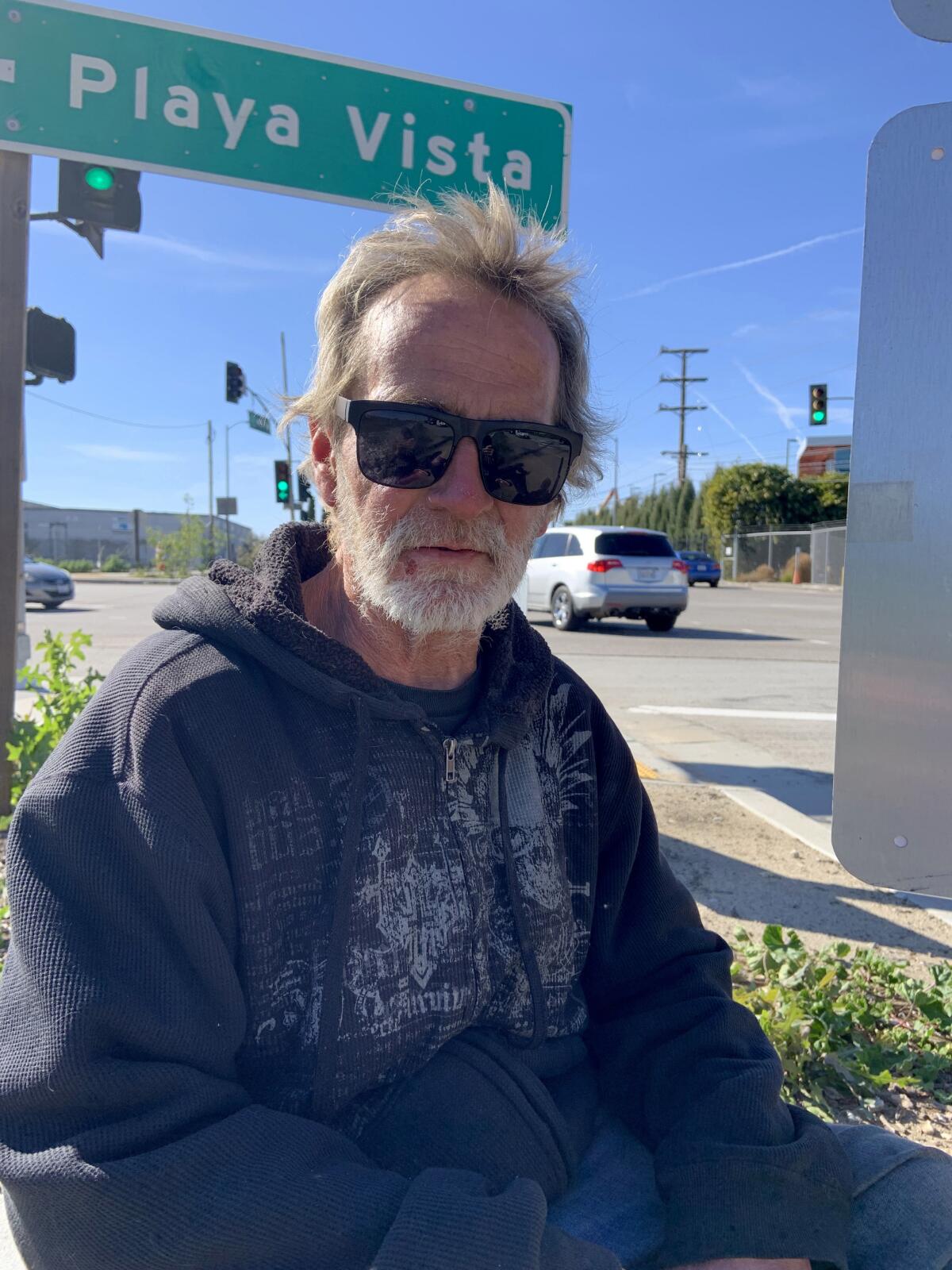 A man in sunglasses, with a street sign behind him that says "Playa Vista"