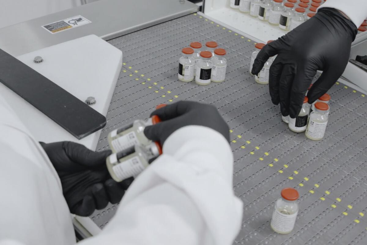 Workers at Regeneron Pharmaceuticals inspect vials of the company's experimental antibody treatment for COVID-19.