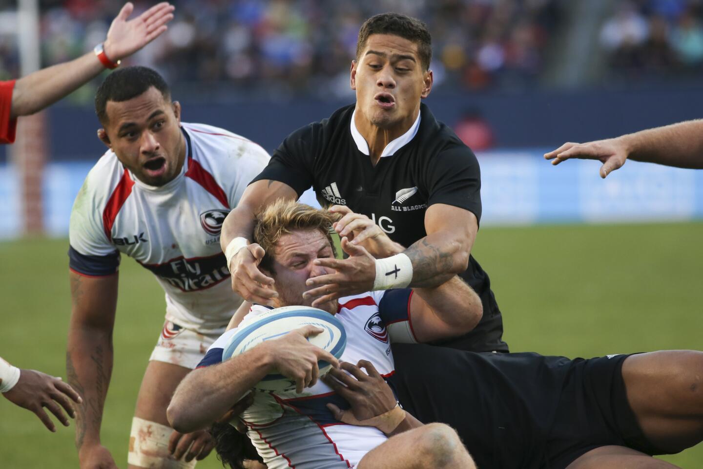 USA Eagles' Tom Coolican (16) gets tackled by New Zealand All Blacks' Julian Savea (23) and Augustine Pulu (21) during the second half.