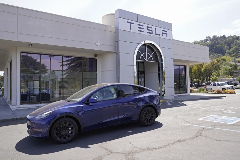 FILE - In this April 2, 2021 file photo two women in an electric car drive into a Tesla delivery location and service center in Corte Madera, Calif. California’s Department of Motor Vehicles is reviewing whether Tesla is violating a state regulation by advertising its vehicles as being fully autonomous without meeting the legal definition of self-driving The department says Monday, May 17, 2021 that the regulation prohibits advertising vehicles for sale or lease as autonomous if the regulation isn’t met. (AP Photo/Eric Risberg,File)