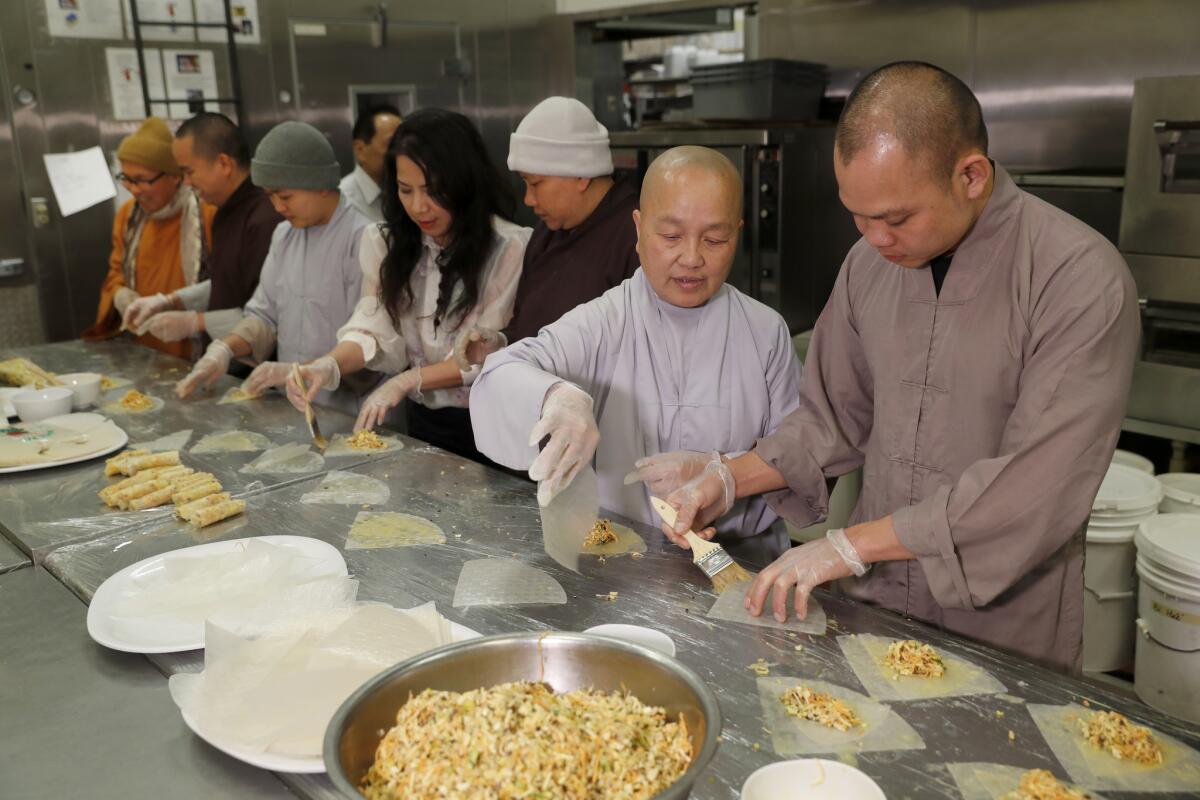 Buddhist monk Thich Thien Niem, right, head chef, makes summer rolls with Buddhist nun Thich Dieu Tanh, manager. Fourth from right is Chau Haller, owner of Bamboo Bistro.