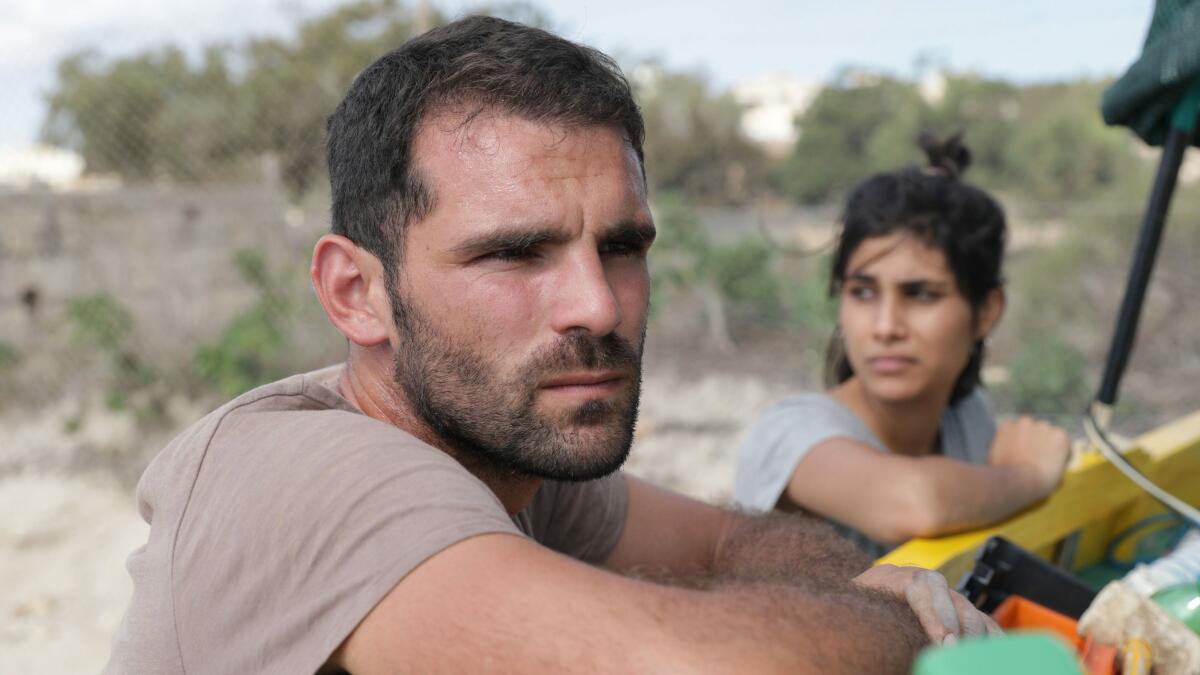 A man and a woman lean on a boat in the movie “Luzzu.”