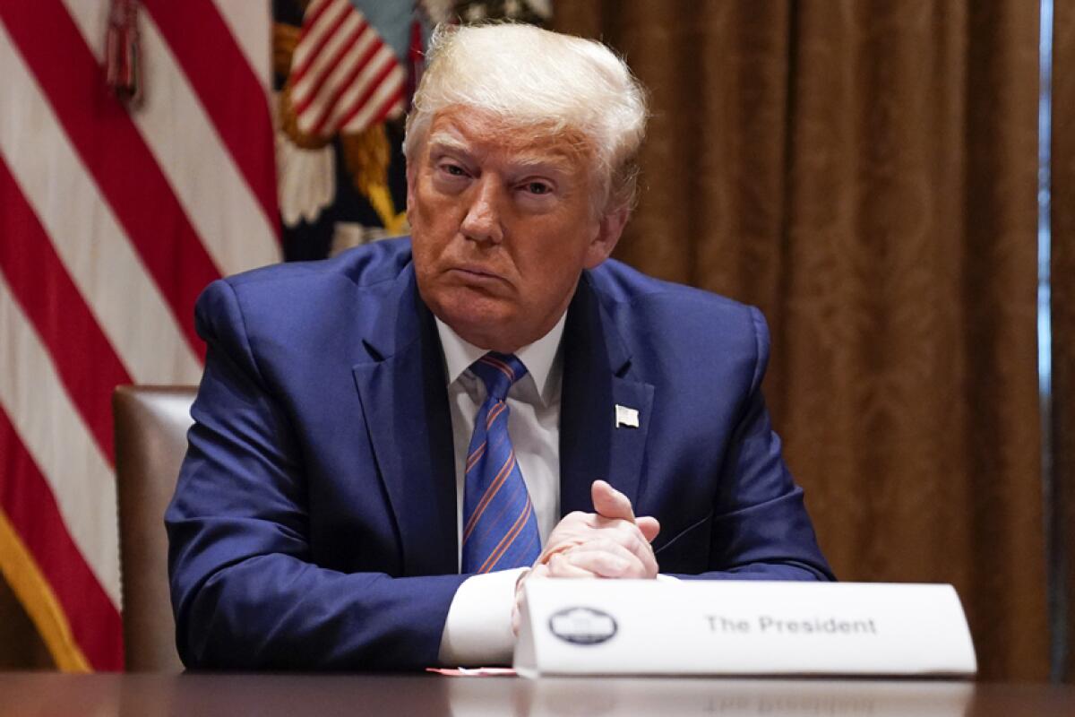President Trump, in a blue suit, sits at a roundtable. 