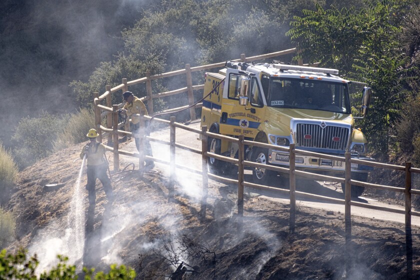 FILE - In this Monday, July 6, 2020 file photo, firefighters douse hot spots along Agua Dulce Canyon road in Agua Dulce, Calif. Emergency personnel are working through high temperatures to contain the Soledad fire in Southern California. In early July 2020, meteorologists say temperatures will be stuck with above normal temperatures through the month if not longer. (David Crane/The Orange County Register via AP)