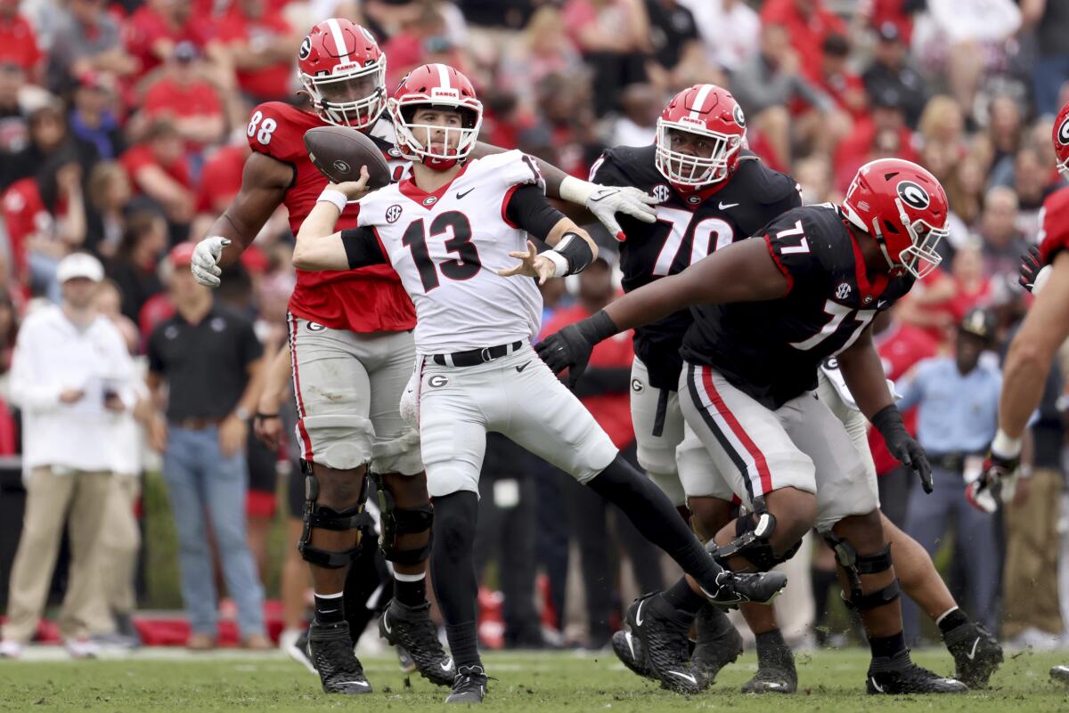 FILE - Georgia quarterback Stetson Bennett (13) attempts a pass under pressure from Georgia defensive lineman Jalen Carter (88) during Georgia's spring NCAA college football game, Saturday, April 16, 2022, in Athens, Ga. The 2021 season was filled with surprising contenders and conference champions. Another season with that much volatility in 2022 seems unlikely. (Jason Getz/Atlanta Journal-Constitution via AP, File)