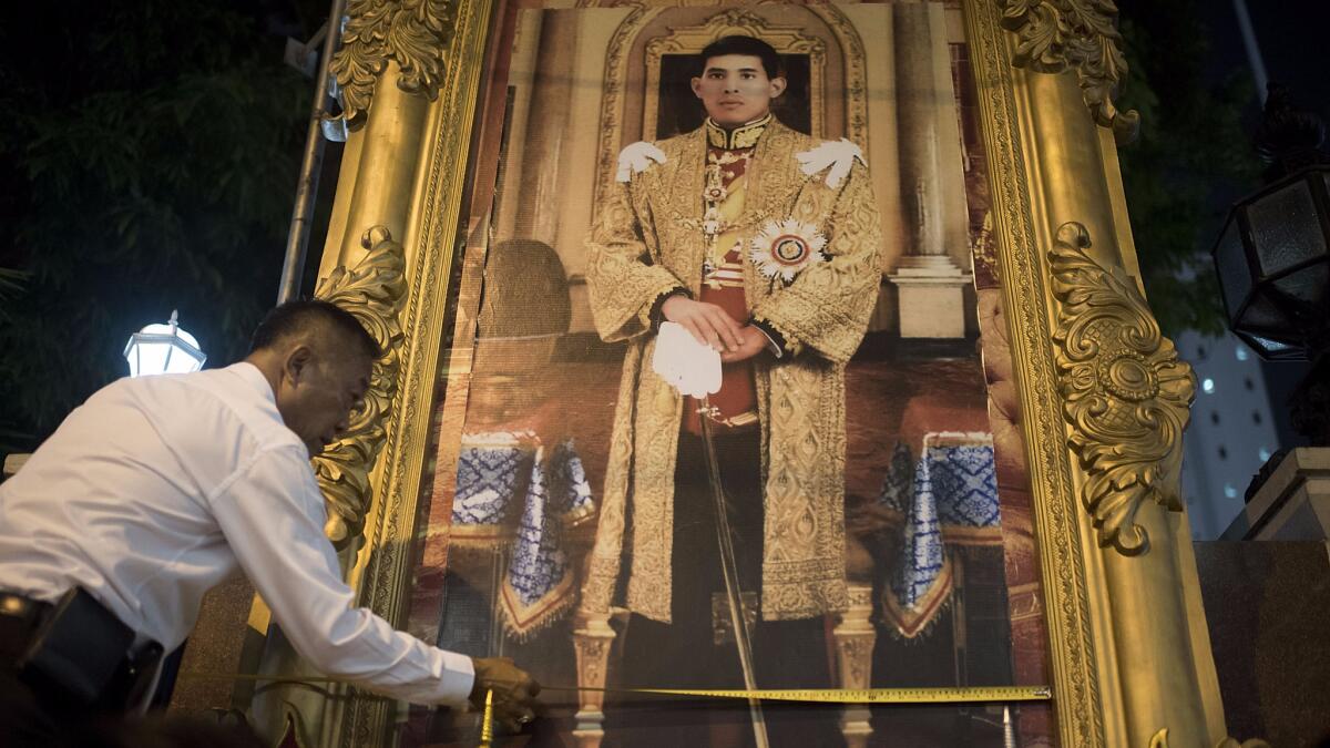 An official installs a new portrait of Crown Prince Maha Vajiralongkorn at the Thai police headuarters in Bangkok on Oct. 14, 2016.