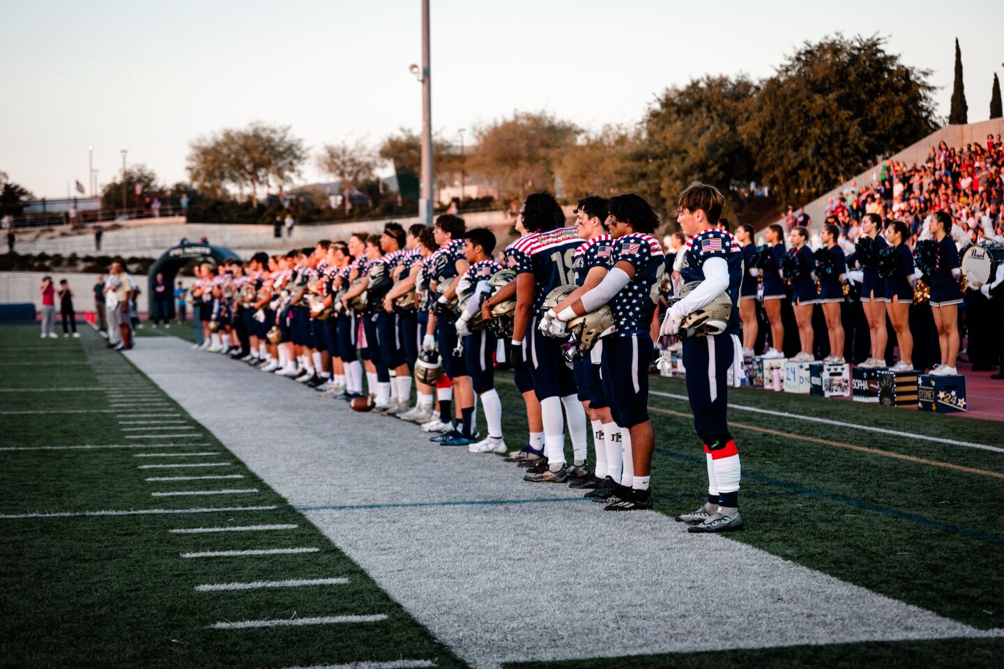 The varsity football team lines up as the National Anthem is played. The colors are presented by a military band, the Del Norte band and the Oak Valley Middle School band.