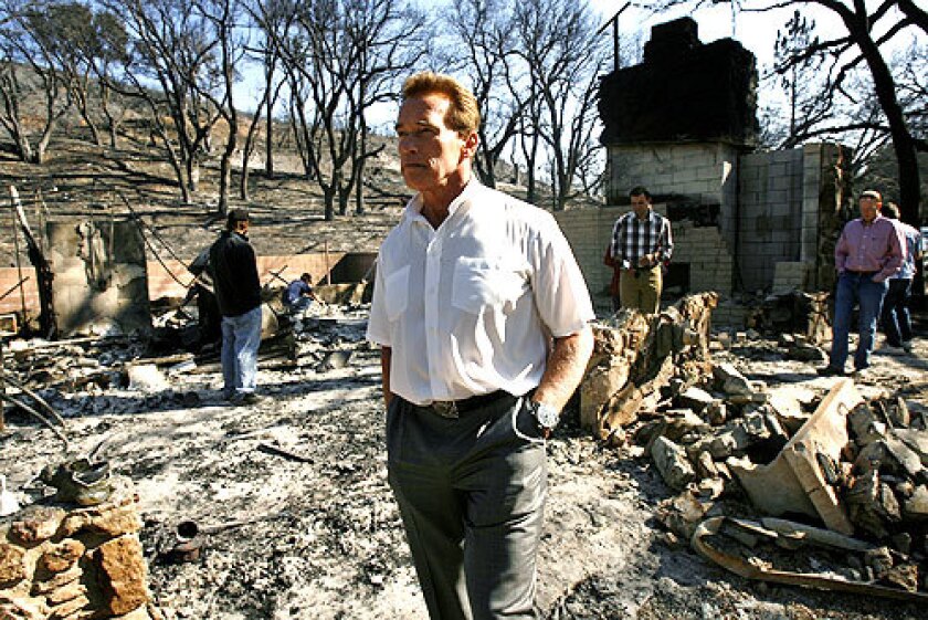 California Gov. Arnold Schwarzenegger examines a house owned by Phil Reddish Sunday, Oct. 29, 2006, which was destroyed by the Esperanza fire in the community of Twin Pines north of Banning, Calif.
