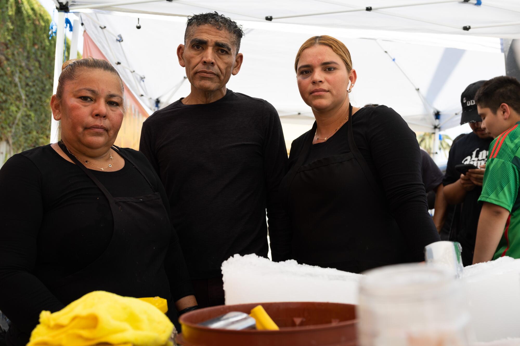 From left, Lucia Duran, 48, Isaiah Vasquez, 54, and Karina Ceron, 31, stand at their raspado cart in