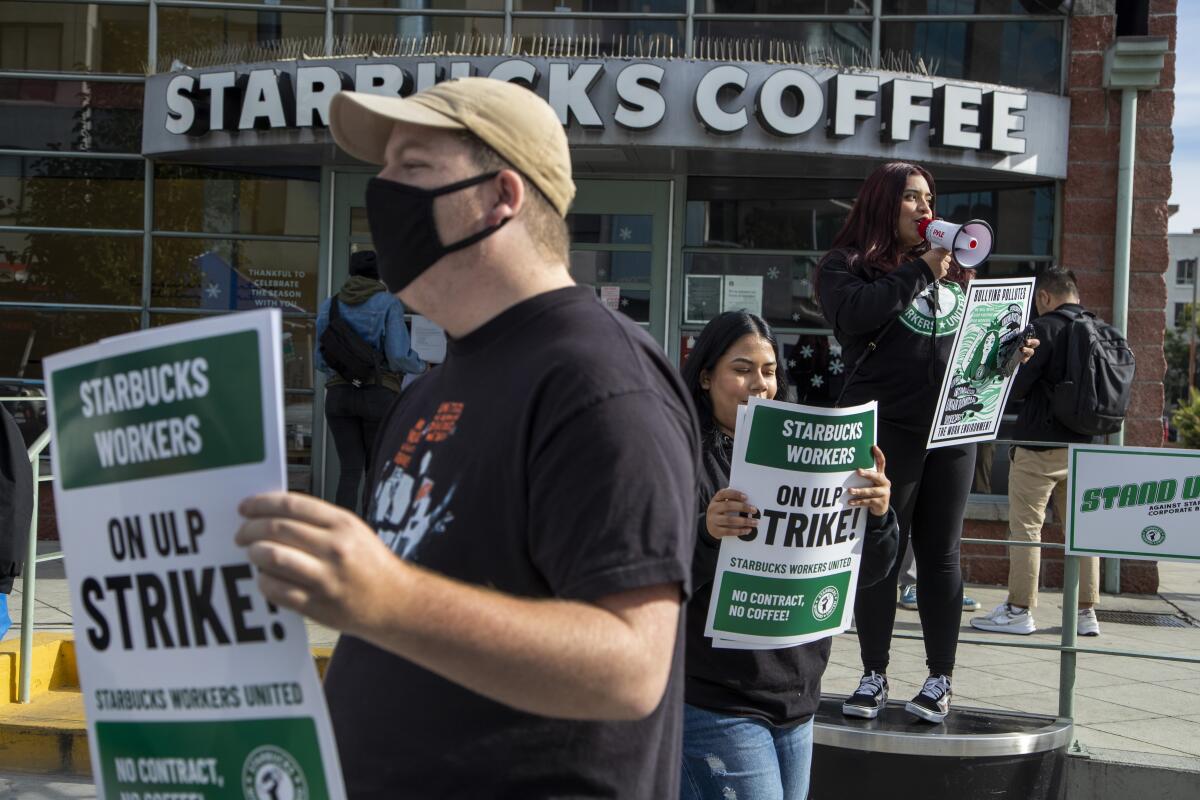 Employees, supporters and labor organizers hold signs as they strike at a Starbucks location in Los Angeles.
