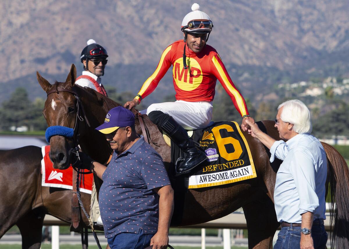 Jockey Edwin Maldonado shakes trainer Bob Baffert's hand while sitting atop Defunded at Santa Anita.