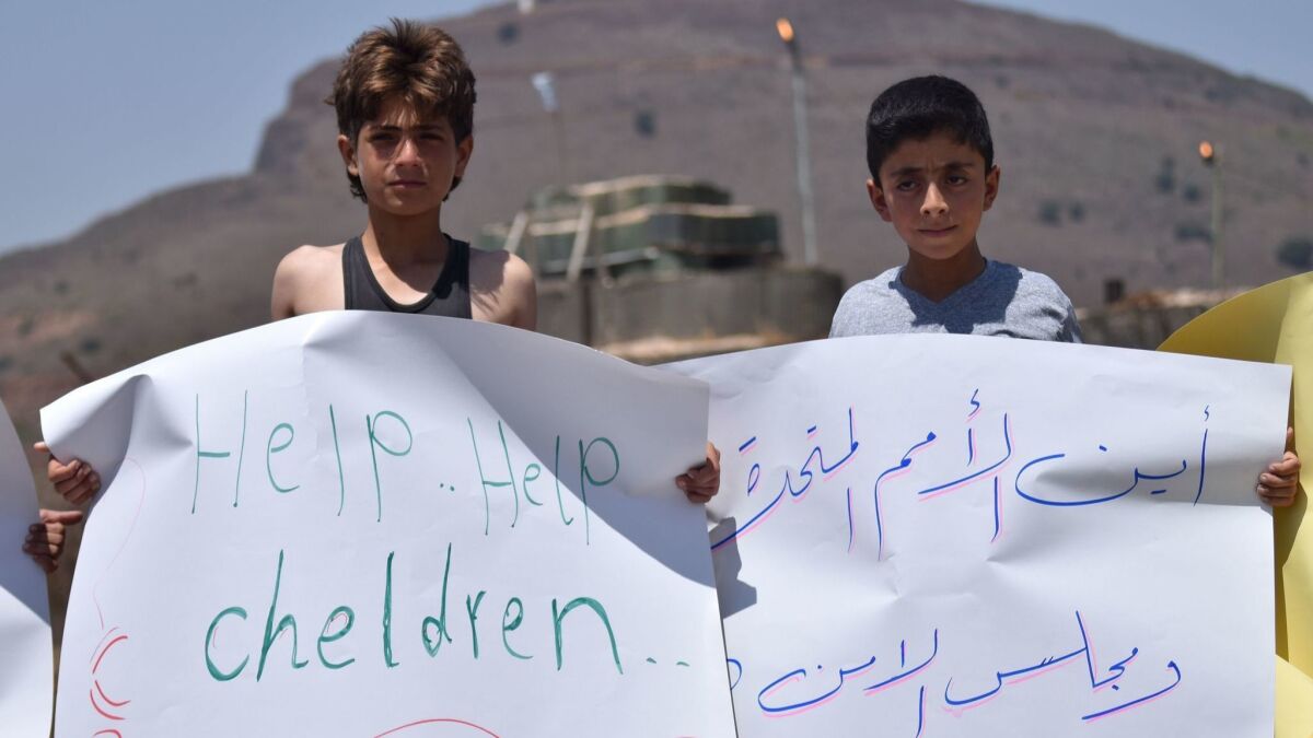 Displaced Syrian children make their plea at a July 4, 2018, protest in front of a U.N. base in the southwestern province of Quneitra. The Arabic sign reads: "Where is the United Nations and the Security Council?"