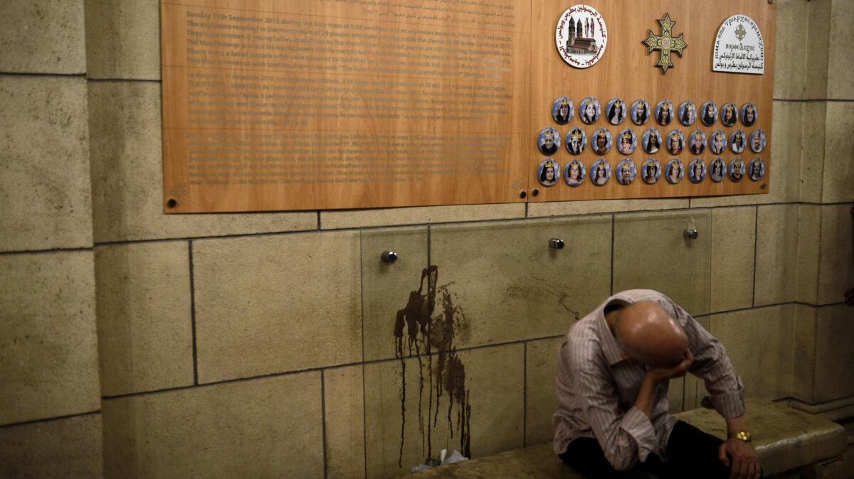 A man sits in the courtyard outside the chape of the Cairo Cathedral during easter mass. The bloodstain existed since the bombing in December 2016 that left 29 dead.