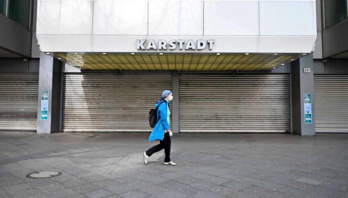 A woman wearing a face mask walks past a closed department store in Berlin on March 18, 2020. 
