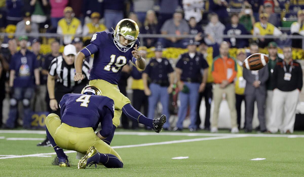 Notre Dame 's Justin Yoon (19) kicks the winning 23-yard field goal out of the hold of Montgomery VanGorder (4) during the final seconds against Miami on Saturday.