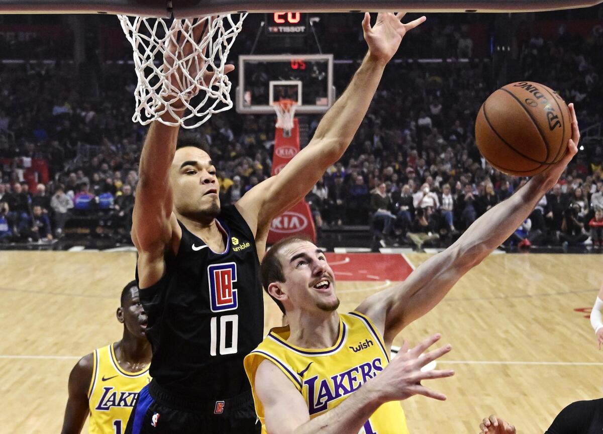 Lakers guard Alex Caruso, right, shoots as Clippers guard Jerome Robinson defends during the first half on Friday at Staples Center.