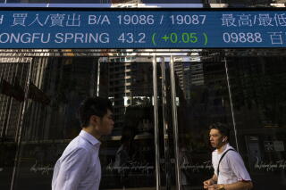 Pedestrians pass an electronic board displaying prices at the Hong Kong Stock Exchange