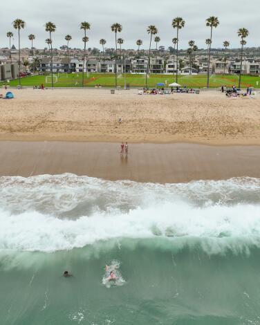 Newport Beach, CA - June 07: A body surfer dives under the waves at Balboa Beach near the Balboa Pier in Newport Beach Friday, June 7, 2024. (Allen J. Schaben / Los Angeles Times)