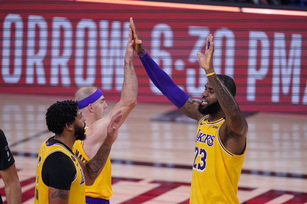 LeBron James (23) celebrates with Anthony Davis, left, and Alex Caruso after beating the Rockets on Sept. 10.