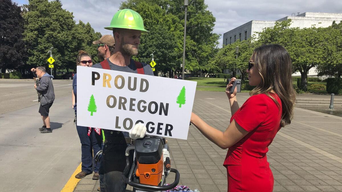 A TV reporter interviews self-employed logger Bridger Hasbrouck outside the Oregon State House in Salem on Thursday.