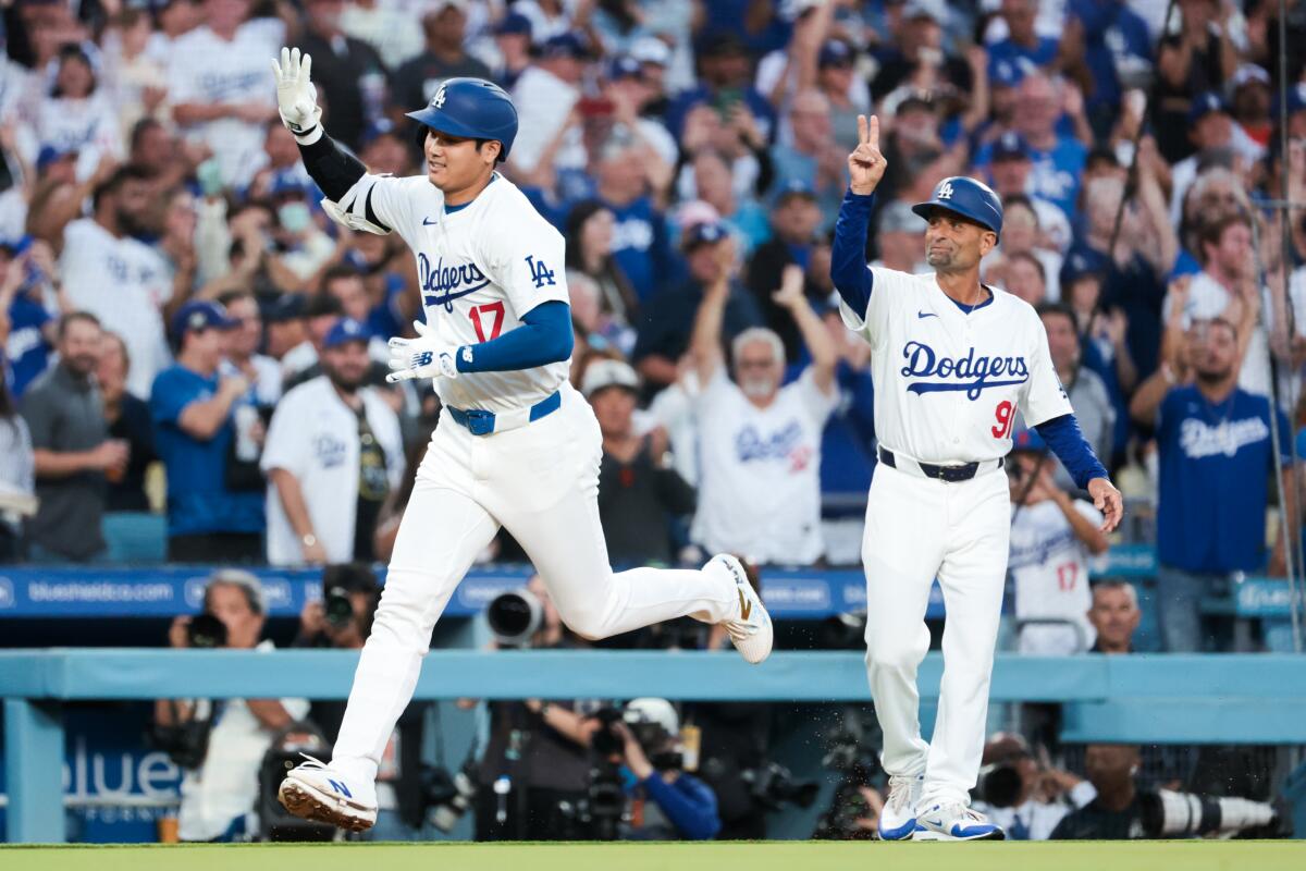 Shohei Ohtani rounds the bases in front of third base coach Dino Ebel after leading off the game with a homer.