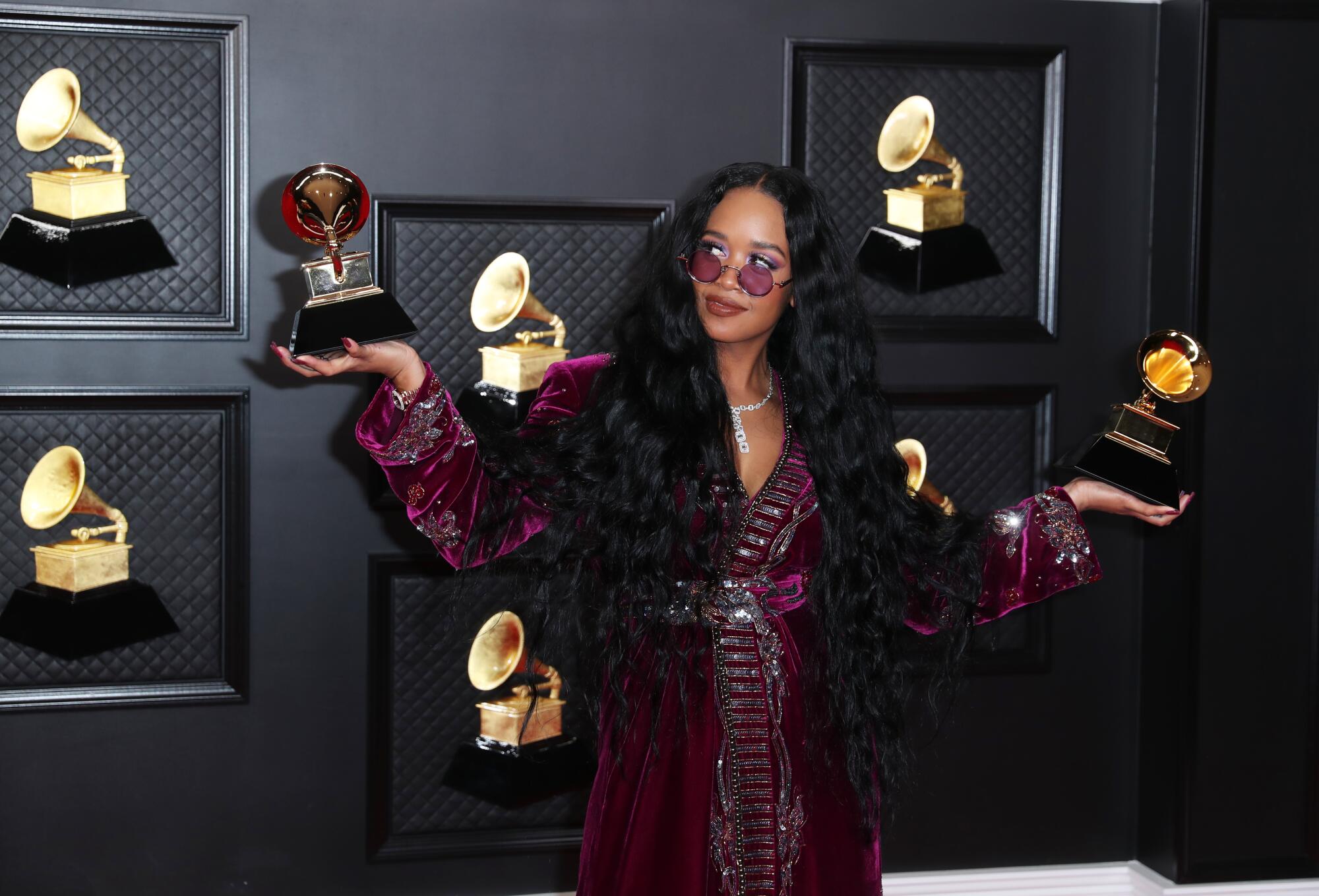 H.E.R. holds her two Grammy awards.