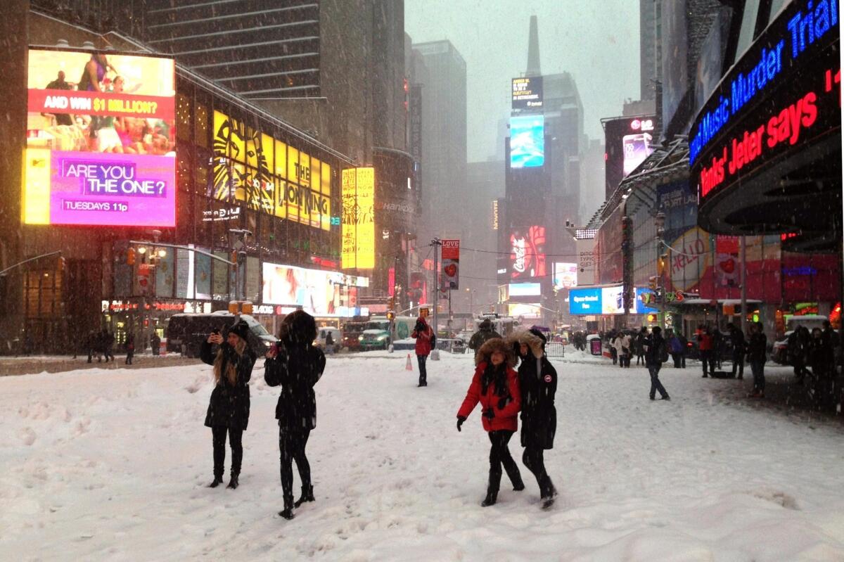 In New York, snow was falling in Times Square on Thursday morning. By midday, the city had gotten nearly 10 inches.