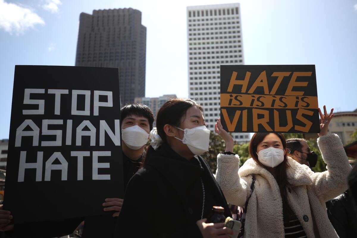 People hold signs that say "Stop Asian hate" and "Hate is virus."