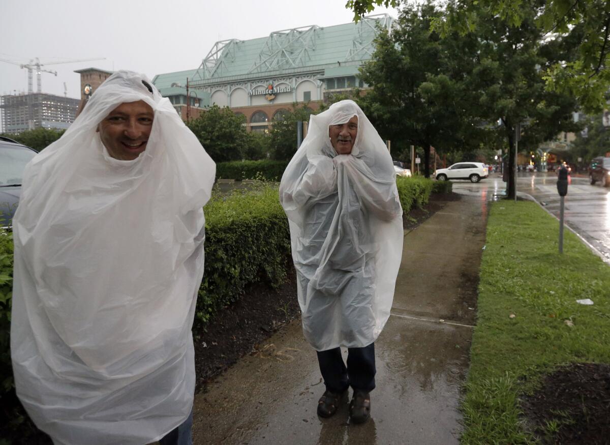 Houston Astros fans make their way away from a very wet Minute Maid Park, where rain started pouring in through the roof and water gushed up through storm grates.