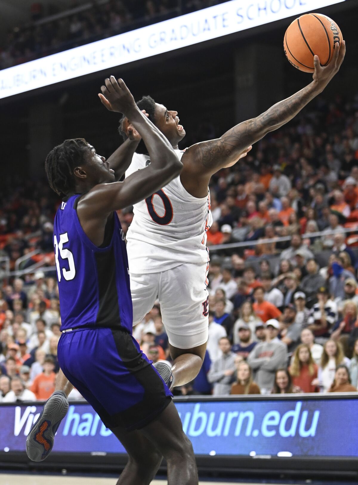 Auburn guard K.D. Johnson (0) scores two points as North Alabama forward Pape Momar Cisse (35) defends during the first half of an NCAA college basketball game Tuesday, Dec. 14, 2021, in Auburn, Ala. (AP Photo/Julie Bennett)