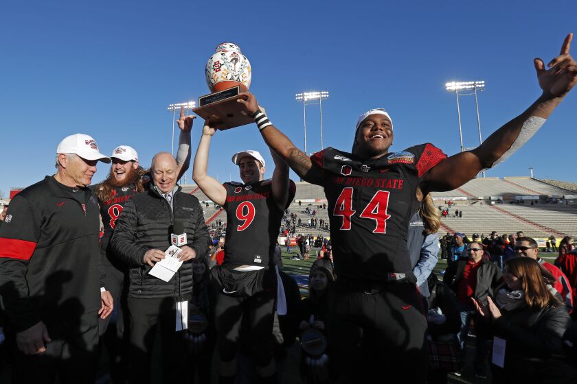 San Diego State linebacker Kyahva Tezino (44), quarterback Ryan Agnew (9), tight end Parker Houston, second from left, and coach Rocky Long, left, celebrate with the trophy after their team beat Central Michigan in the New Mexico Bowl NCAA college football game on Saturday, Dec. 21, 2019 in Albuquerque, N.M. (AP Photo/Andres Leighton)